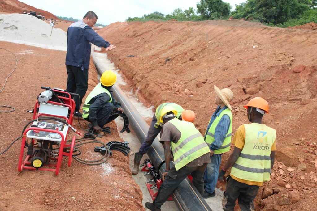 Ouvriers intervenant sur une canalisation enterrée lors des travaux du Port Sec de Ferkessédougou.