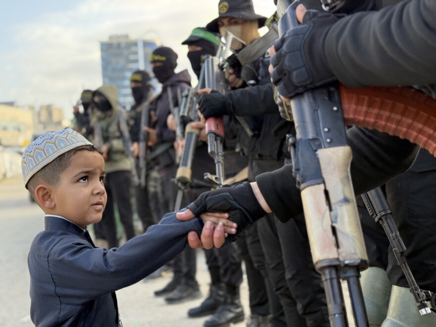 Un garçon palestinien serre la main de combattants du Hamas.