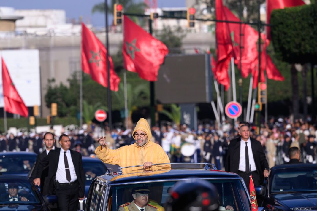 Le Roi Mohammed VI saluant la foule depuis le véhicule royal, sous les drapeaux marocains lors de l'ouverture de la 12e Législature.