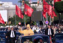 Du vote au jugement de l’Histoire : les trois dimensions du discours royal du 9 octobre Le Roi Mohammed VI saluant la foule depuis le véhicule royal, sous les drapeaux marocains lors de l'ouverture de la 12e Législature.